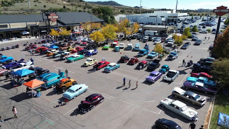 Rows of colorful classic cars at an outdoor car show, seen from above